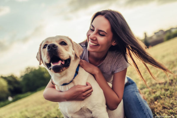 Lächelnde Frau, welche einen Hund umarmt